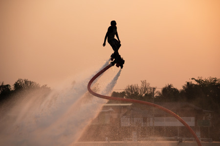 The new spectacular sport,Silhouette of a man showing the flyboard in the river of Thailandの写真素材