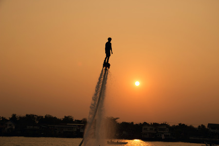 The new spectacular sport,Silhouette of a man showing the flyboard in the river of Thailandの写真素材