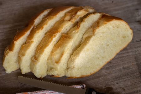 Bread slice with bread knife on wooden background