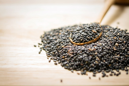 Black sesame in wooden spoon on wooden board ; Food backgroundの写真素材