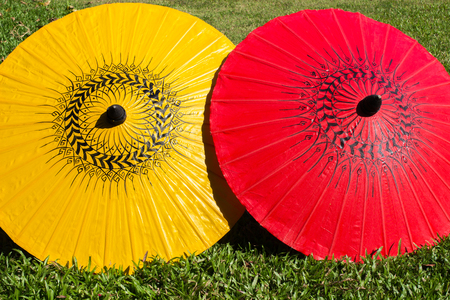 Colorful umbrellas on grass field ; Bo-sang umbrella handicraft made from paper of Chiang Mai, Thailand.の写真素材