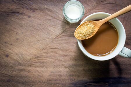 Cup of coffee with brown sugar and milk on wooden backgroundの写真素材
