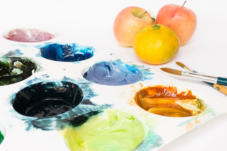 Messy palette with watercolor paints prepare to painting an apple and orangeの写真素材