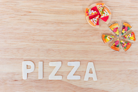 Miniature clay pizza and wooden white word PIZZA on wooden board background (overhead shot)の写真素材