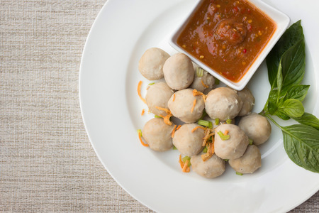 Boiled pork balls with sweet spicy sauce in white plate on gray table mat; top viewの写真素材