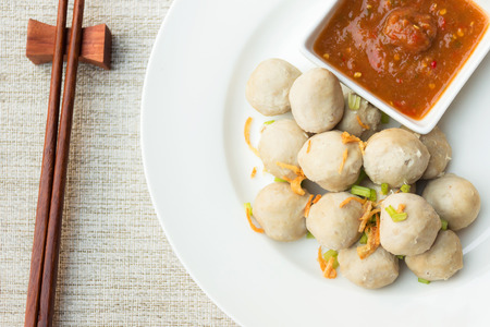 Boiled pork balls with sweet spicy sauce in white plate on gray table mat; top viewの写真素材