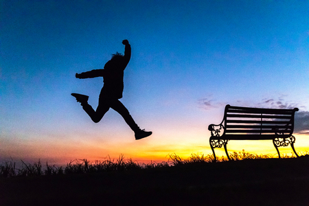 Silhouette of happy boy jumping against beautiful twilight sky over a mountain. Freedom enjoyment concept.の写真素材
