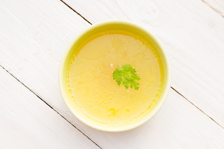 Bowl of chicken broth on rural tableの写真素材