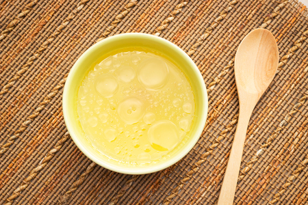 Bowl of chicken broth on rural table with wooden spoonの写真素材