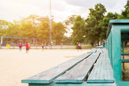 Green old wooden seat sport, stand cheer and active young volleyball players at the sand outdoor court with tree background (selective focus)の写真素材