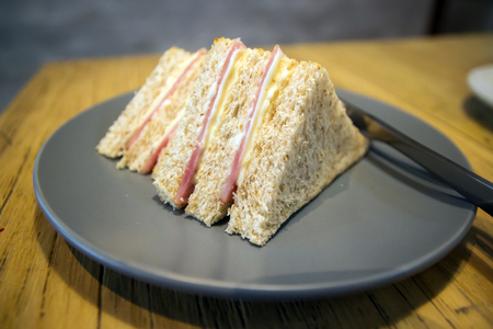 Whole wheat sandwich toast with ham and cheese on a wooden table at coffee shopの写真素材