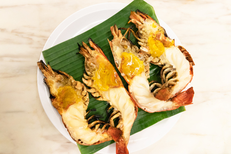 Charcoal grilled giant river prawn usually serve with spicy seafood sauce on green banana leaf in restaurant; Thailand's popular dishes.の写真素材