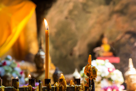 Candle light in a cave temple to worship buddha.の写真素材