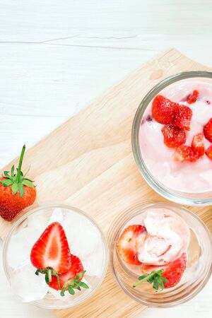 Fresh juicy strawberry with yogurt in a glass bowl and fresh strawberry on ice on rustic wood table with copy spaceの写真素材