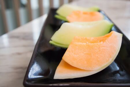 Juicy melon sliced on black porcelain tray.の写真素材