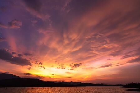 Dramatic sunset sky above a surface of lake, natural background.の写真素材