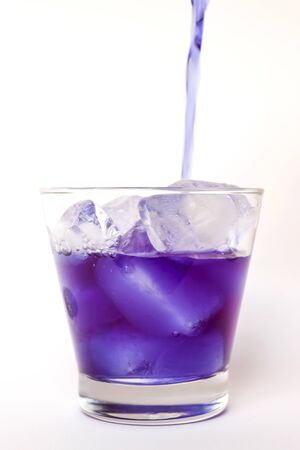 Pouring butterfly pea juice on ice in transparent glass isolated on white backgroundの写真素材