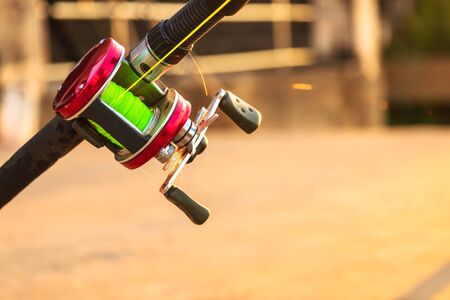 Closeup of fishing rod and reel with beautiful sunlight on background.の写真素材