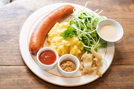 Grilled sausages and mash potato serving with ketchup, mustard and organic young sunflower sprouts.の写真素材