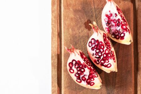 Pomegranate (Punica granatum) slice on wooden cutting board.の写真素材