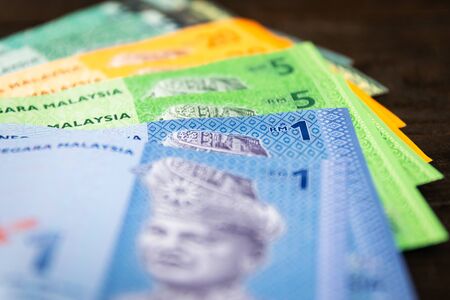 Various type of Malaysia Currency (MYR): Stack of Ringgit Malaysia bank note on dark brown a wooden table background. (There are one, five, twenty and fifty)の写真素材