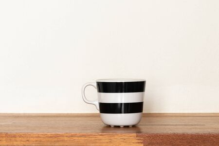 Black and white mugs on wooden shelf.の写真素材