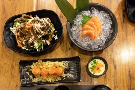 Salmon meal on table; salmon steak, sashimi, maki, steam egg and salad with crispy skin salmon. Healthy food with rich in omega-3 meal.の写真素材