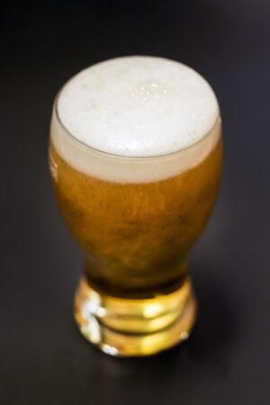 Beer in a tall glass isolated on black background (selective focus)の写真素材