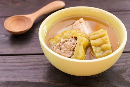 Bitter gourd soup with pork ribs in bowl on wood table.の写真素材