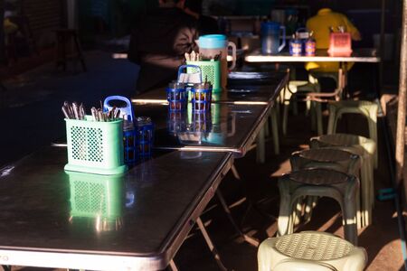 Table and chair of noodle or food street vendor with shade of sunlight. Thai street food shop.の写真素材
