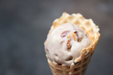 Woman hand holding coffee almond flavor ice cream cone for refreshing.