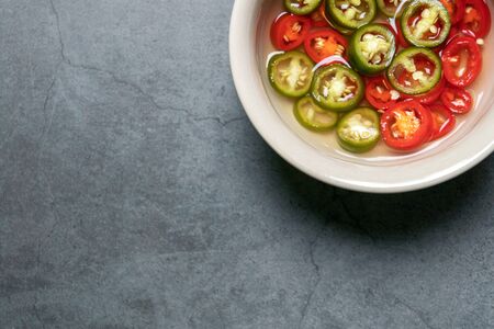 Green and red pickled chili in vinegar with copy space on background. Top viewの写真素材