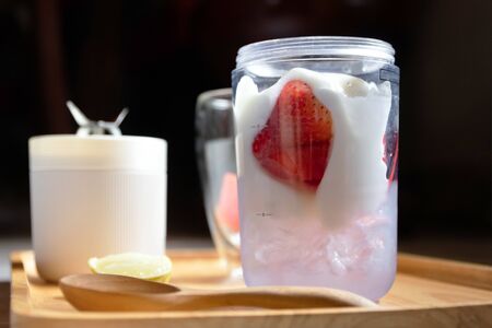 Healthy fruits with portable blender on wooden tray getting ready for making a smoothie. Fresh strawberry and watermelon with ice; healthy and fresh concept.の写真素材
