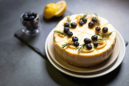 Homemade cheesecake with fresh blueberry and candied lemon on black stone background.の写真素材