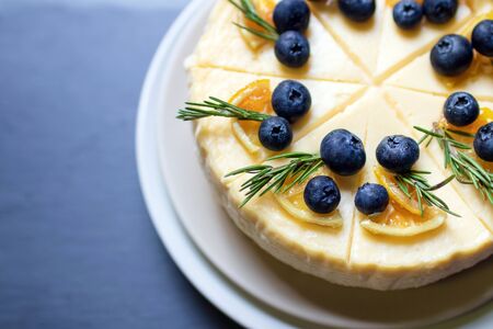 Homemade cheesecake with fresh blueberry and candied lemon on black stone background.の写真素材
