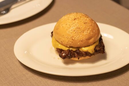 Delicious cheese burger; beef with melting of cheese in warm light at restaurant.の写真素材