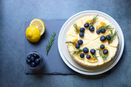 Homemade cheesecake with fresh blueberry and candied lemon on black stone background.の写真素材