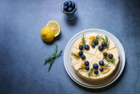 Cheesecake with fresh blueberry and candied lemon on black stone background.の写真素材