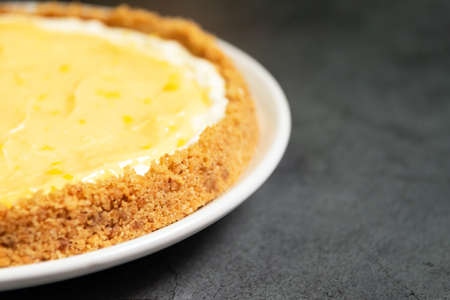 Delicious homemade honey lemon cheese pie and juicy lemoncurd on plate with copy space on black...