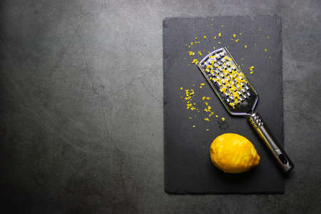 Grater and lemon zest on black background with copy space.の写真素材