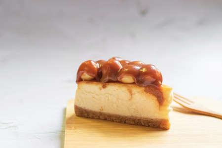 Caramel macadamia cheesecake with wooden fork on wooden tray.の写真素材