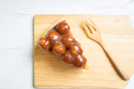 Caramel macadamia cheesecake with wooden fork on wooden tray.の写真素材