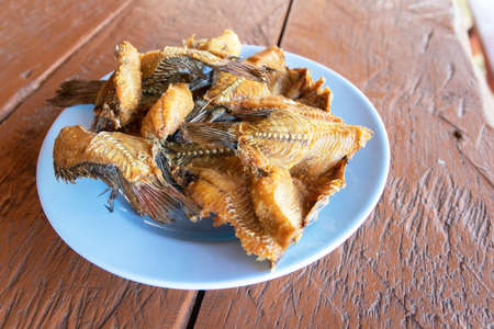 Crispy deep fried river fish in dish o wooden table.