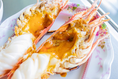 Grilled giant river prawn usually serve with spicy seafood on plate in restaurant, taken with natural light. (selective focus)の写真素材