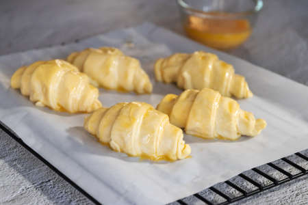 Pastry chef baking croissants on white table with sunlight through from window.