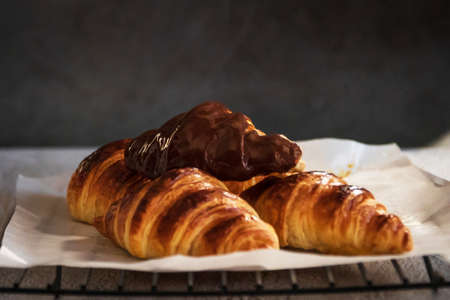 Dark chocolate croissants with nut and flower of salt on top in vintage dark stone background. Tasty...