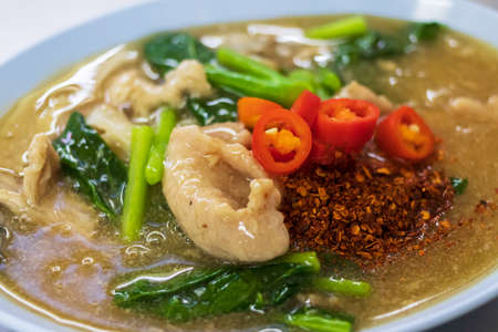 Fried noodles with pork and kale in gravy sauce (Rad-Na Moo) add pickled chili in vinegar and chili powder.の写真素材