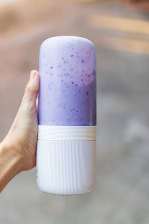 Woman hand holding portable blender with healthy fruits; getting ready for making a smoothie. Fresh blueberry, banana, almond, honey and milk with ice; healthy and fresh concept.の写真素材