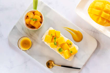 Creamy cheese pie and ripe mango with juicy mango sauce. Sweet and sour dessert sauce. Top view.の写真素材