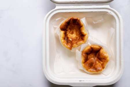 Mini Basque Burnt Cheesecake in paper food container. Top view and copy space on white table background.の写真素材